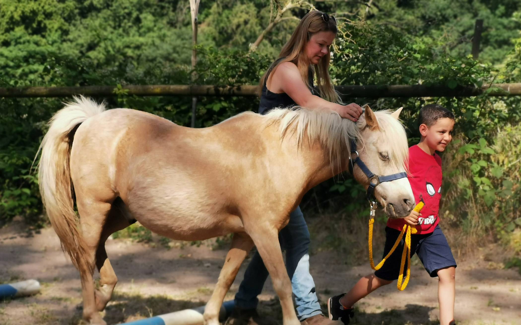  Mohamed führt Pony Goldi über den Kinder-Action-Parcours. Western- und Pferdetrainerin Svenja Clauberg hat dabei beide im Blick.  