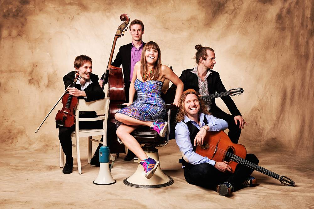  Was spielen eine franko-amerikanische Sängerin, ein polnischer Gitarrist und zwei musikalische Freunden aus Bonn? Was zunächst wie ein Witz klingt, ist tatsächlich eine wild-mitreißende Mischung aus Gypsy-Jazz, Chansons und Weltmusik. Am Samstag, den 19. August, ab 19 Uhr beim Jubiläumskonzert des Jazzsommers 2023! 
