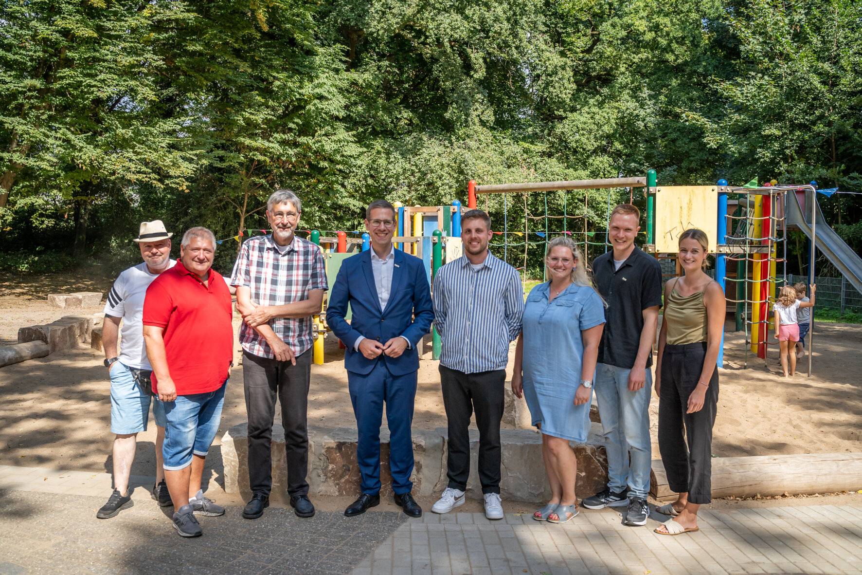  Bürgermeister Christoph Schultz (4.v.l.) eröffnete gemeinsam mit den am Projekt beteiligten Personen und mehreren neugierigen Kindern den neugestalteten Spielplatz Gretenberg in Hochdahl. 