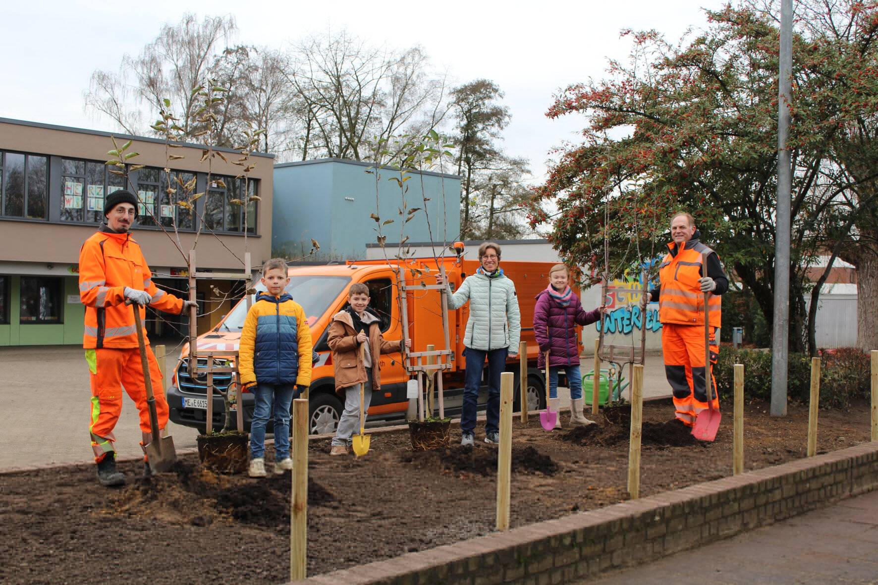  Initiator und Bauhof-Mitarbeiter Marten Wirtz (1.v.r.) pflanzt gemeinsam mit einem Kollegen sowie Standortleiterin Mechthild Histerkamp (3.v.r.) und den Schulkindern Marie (2.v.r.), Kian (5.v.r.) und Fin (4.v.r.). 