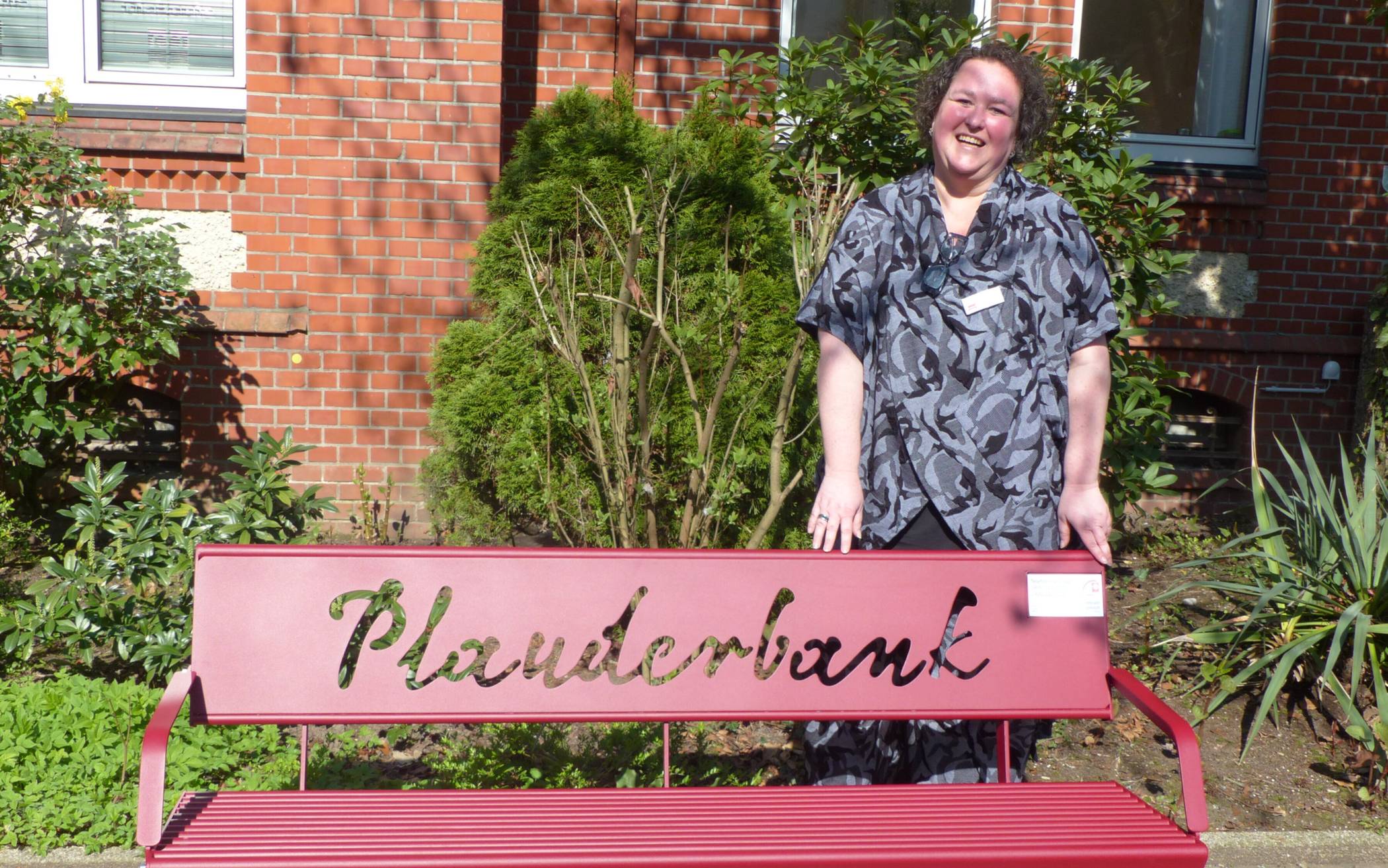 Nicole Förster und die neu eingeweihte Plauderbank gegenüber der Evangelischen Kirche in Alt-Erkrath.