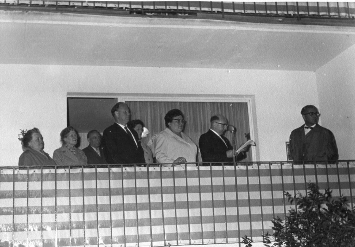  Der Vorsitzende des Heimat- und Verkehrsvereins Herrmann Cüppers grüßt vom Balkon einer Altenwohnung am Marktplatz die junge Stadt. Neben ihm (v.re.) stehen Bürgermeisterin Gertrud Küpper, Stadtdirektor Albert Peters und andere Ehrengäste. Ganz rechts steht Hausmeister Johann Moritz. 